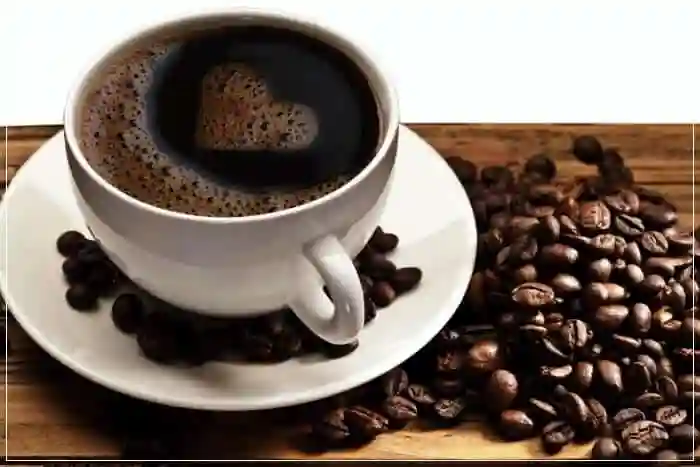 black coffee in cup with beans next to it