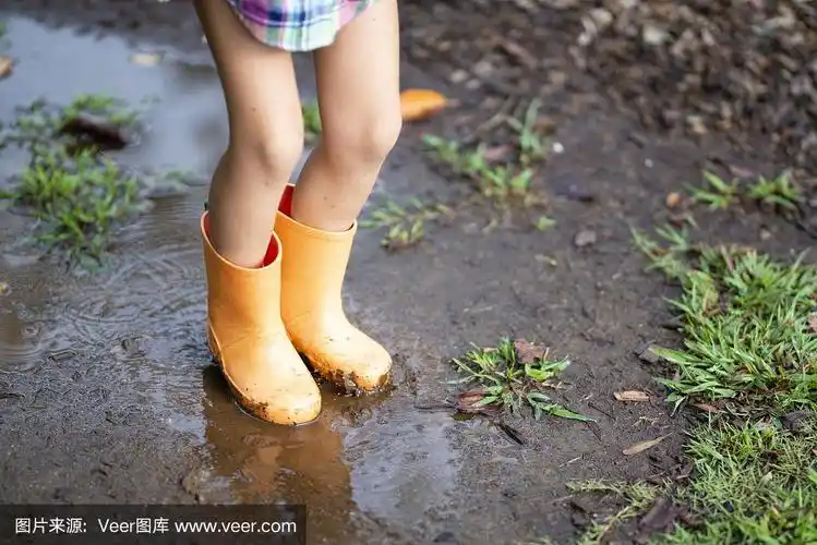 孩子们的脚踩着水坑玩