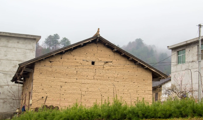 这栋土墙老房子,是上个世纪五六十年代的记忆,如今被紧紧地夹在两栋新