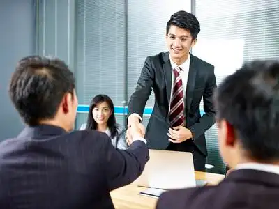 两名亚洲商人在谈判前握手会议桌照片