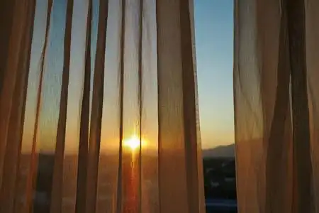 阳光透过窗户内部的白色窗帘照片