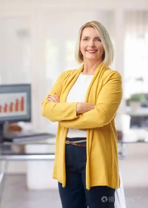 微笑的金融女商人双臂交叉站在办公室.