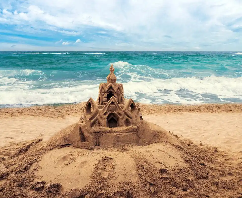 海滩上的沙子城堡,sand castle on beach with water from wave