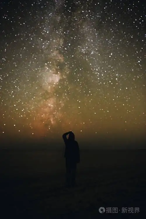 一个孤独的男人的剪影站在海边, 看着星空与银河照片-正版商用图片0rx