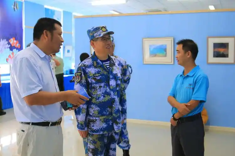 张立陪同三沙市政府副市长徐志飞,西沙某水警区政委胡巨民参观画展
