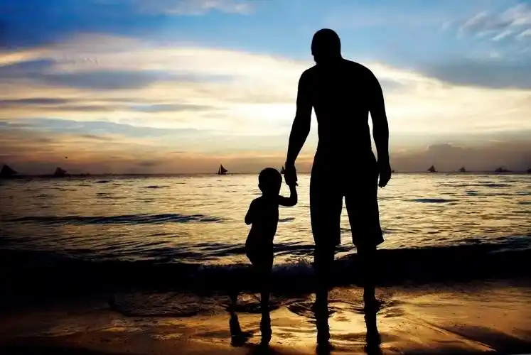 父亲和儿子在夕阳的大海和天空背景上幸福童年孩子幸福的人