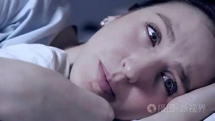 迷人的年轻女子躺在床上,眼泪顺着她的脸流下来.特写