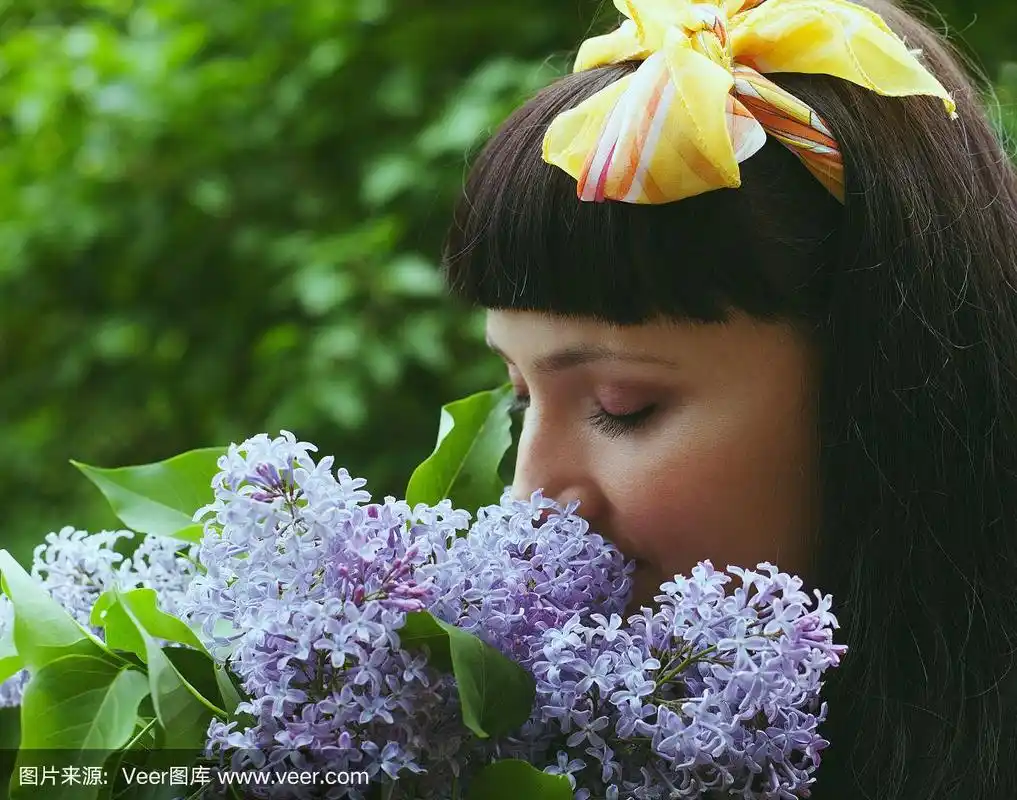 一个年轻女孩闻着丁香花的肖像