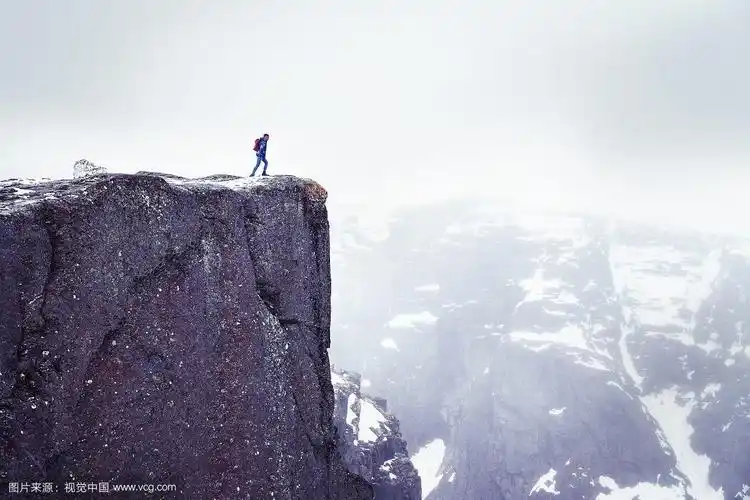 孤独的人在岩石上,旅行者站在悬崖的高边缘,看山在雾.