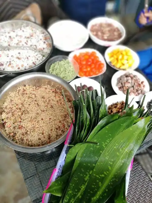 活动现场准备了糯米,粽叶,红枣等材料,支行员工围在一起包粽子.