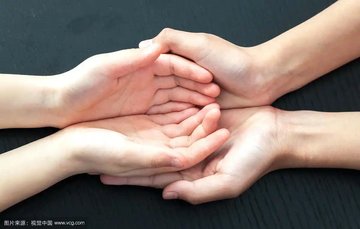 两双紧紧握住的手放在黑色的背景上