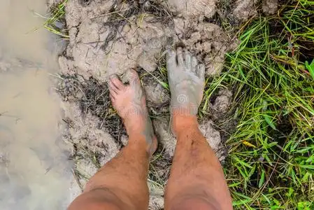 脏的脚踩在泥上照片