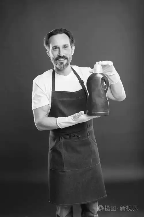 极端洗涤液成熟男人拿着洗涤液瓶管家洗衣服家政工人戴黄色橡胶手套洗