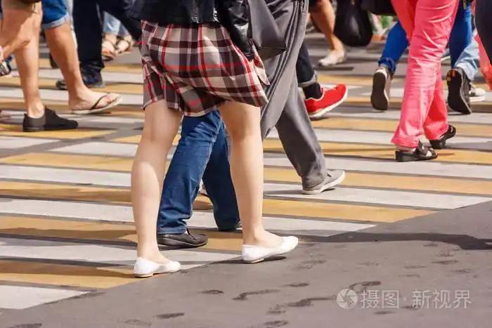 许多人的腿穿过行人过路在繁华的街道上的市中心, 在阳光明媚的夏日