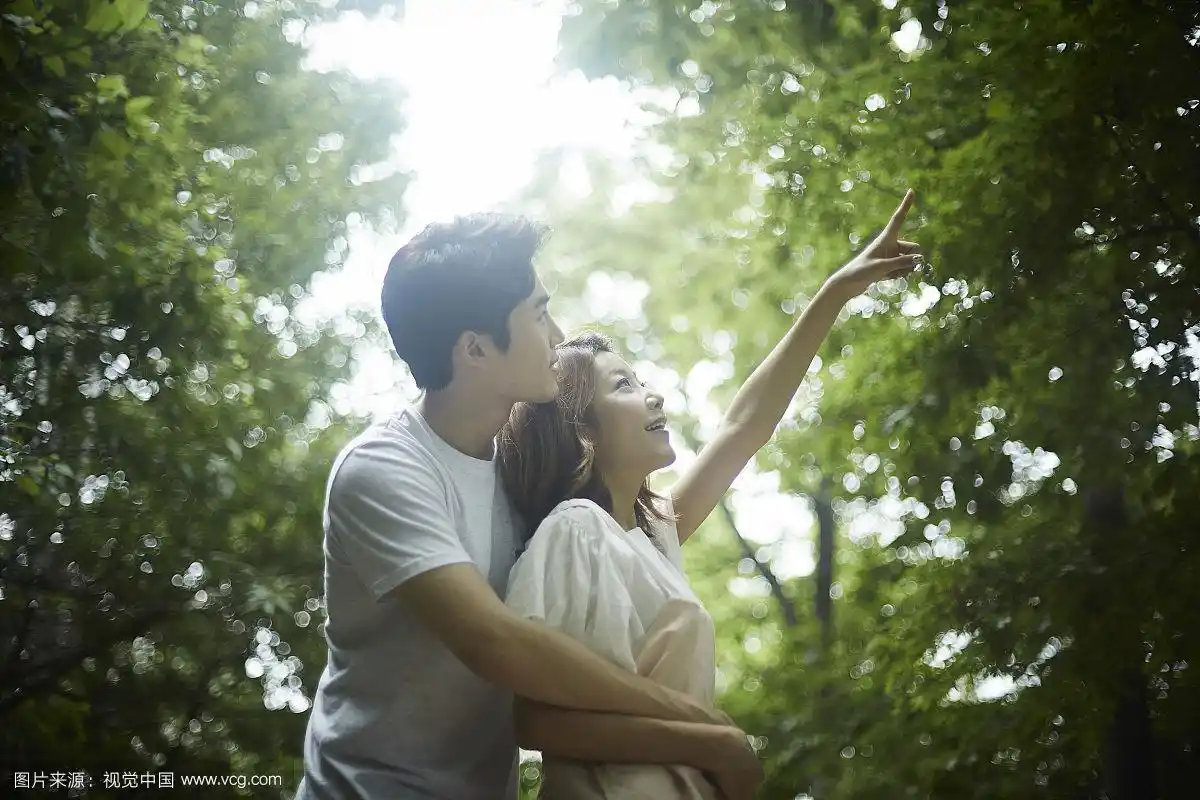 恋爱中的情侣在森林观光,男人从后面拥抱女人