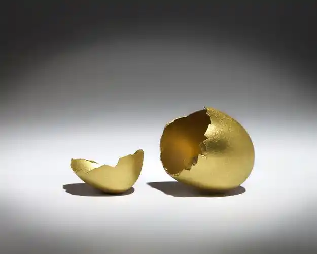破黄金蛋,在聚光灯下的金蛋破裂的壳.