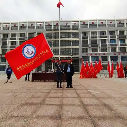 基地学校校长石芳为合山市实验初级中学授基地校旗.