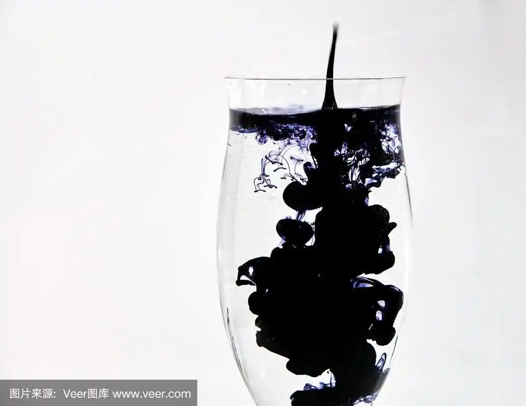 蓝色和黑色的墨水滴进酒杯里的水