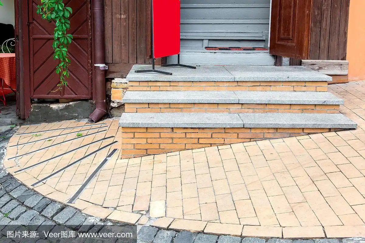 斜坡上的砖门槛和花岗岩台阶通向敞开的木制大门,这是城市街道上木质