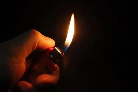 点燃火手点燃打火机在一个黑暗的空间照片
