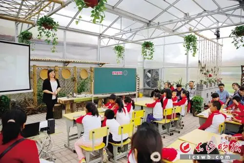 明德小学的孩子们在学校温室大棚里上起科学课,城里老师正在旁听.