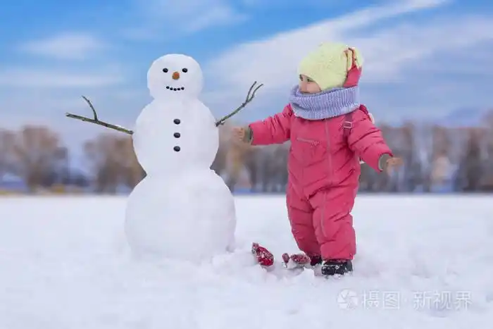 可爱的小女孩在雪亮的地方堆雪人. 冬季户外活动