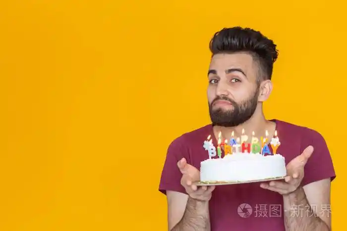 一个留着胡子的年轻男性手里拿着一个写着生日快乐的蛋糕祝贺结婚纪念