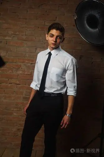 时尚帅气年轻男模白色砖墙前摆姿势