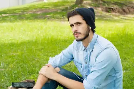 阳光明媚的一天,年轻人用耳机听音乐的肖像.照片