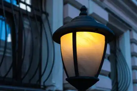 路灯或灯笼的黄色灯光,蓝色背景下的晚街建筑墙面玻璃窗和金属阳台