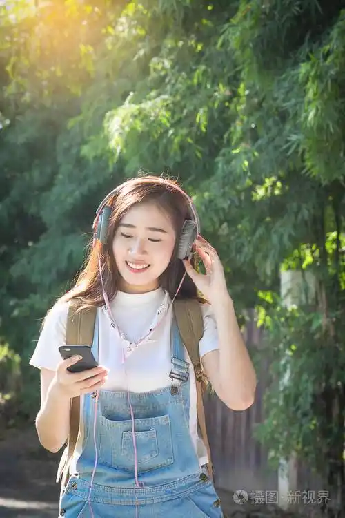 年轻的亚洲时髦戴耳机听音乐通过sm