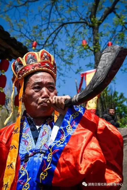 《苗寨吹响牛角号》