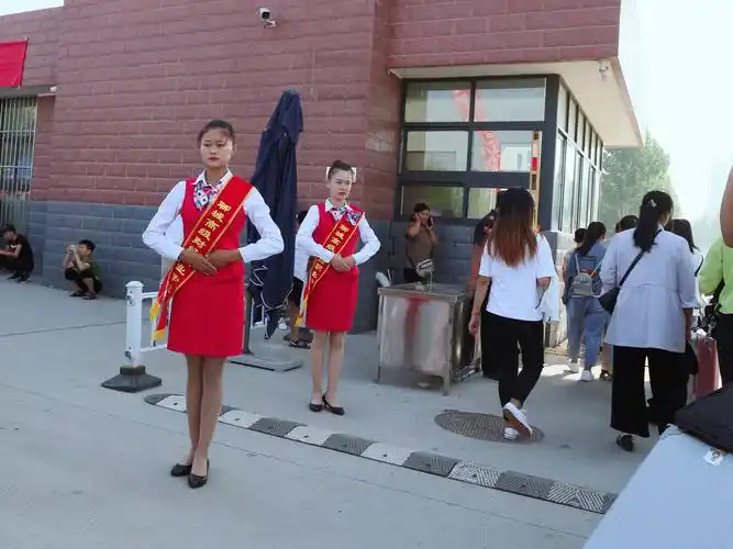 学生志愿者身着礼仪服在校门口迎接