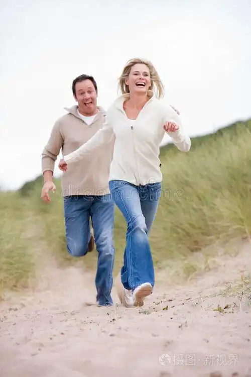 在海滩上微笑着奔跑的夫妇