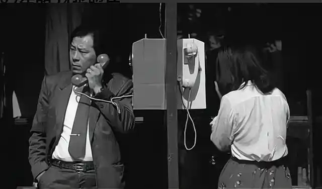 7.1987年,前门,北京,一名男子在路边电话亭打电话.