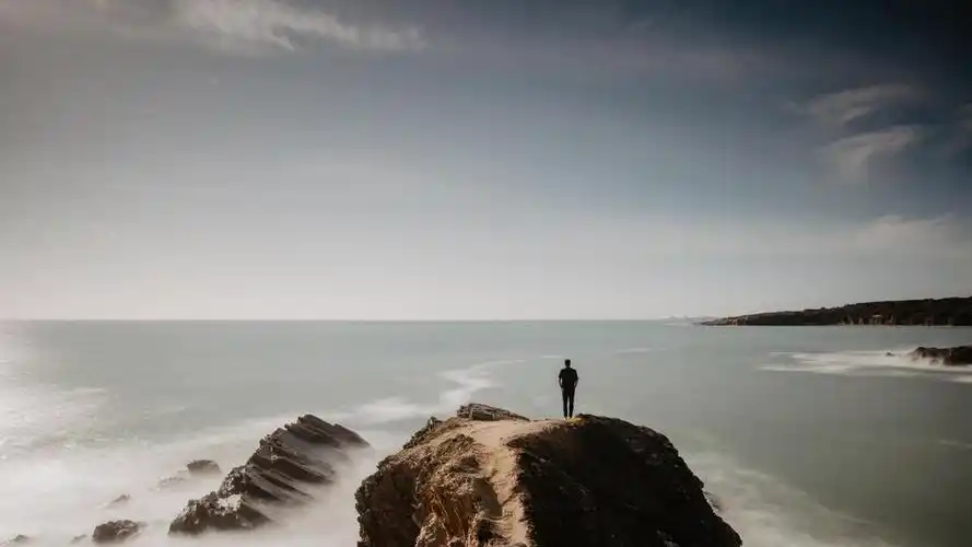 一人站在岩石上面朝大海背景图片灰色伤心少女低头背影背景图片摄影