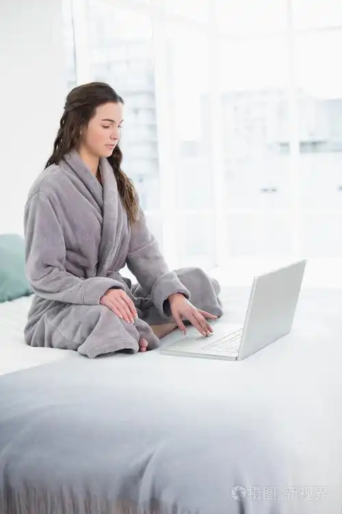 在床上使用笔记本电脑的浴袍休闲布鲁内特
