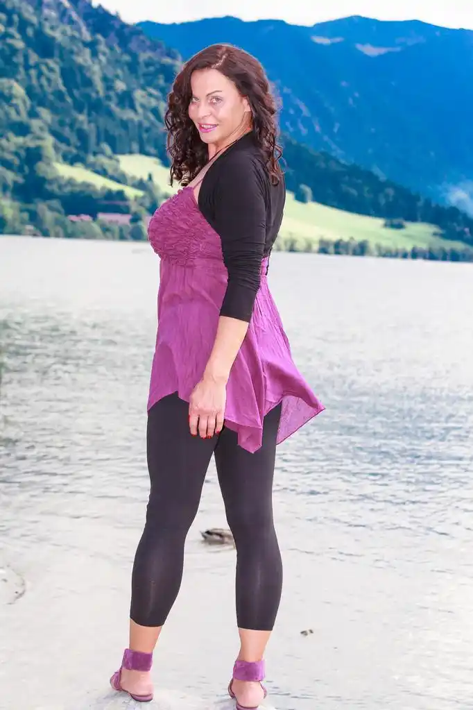 时尚老女人在湖,站在湖边的一块岩石上的丰满, 穿着时尚女子