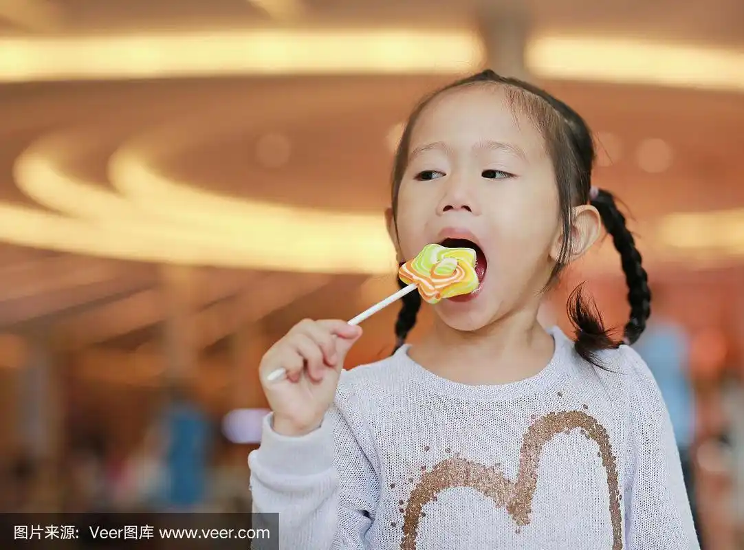 可爱的小女孩在吃明星棒棒糖.