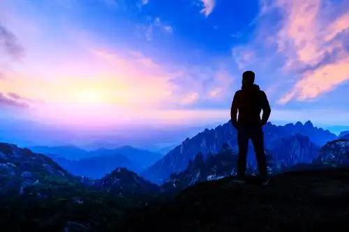 夏季日出时站在山上欣赏大自然的年轻人