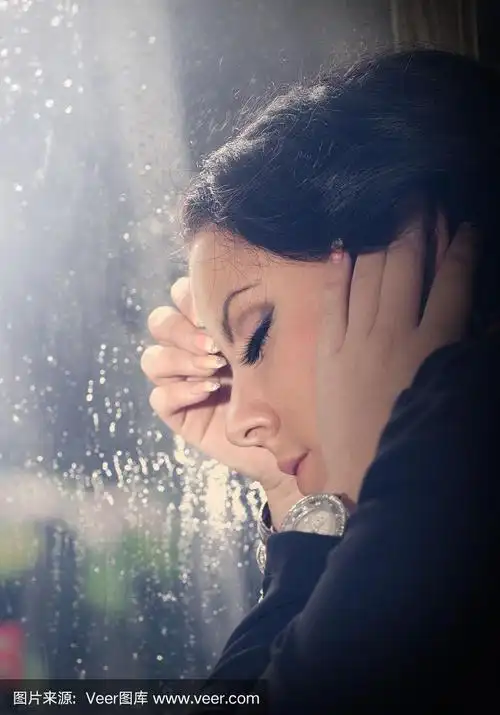 年轻女子透过下雨的窗户向外看