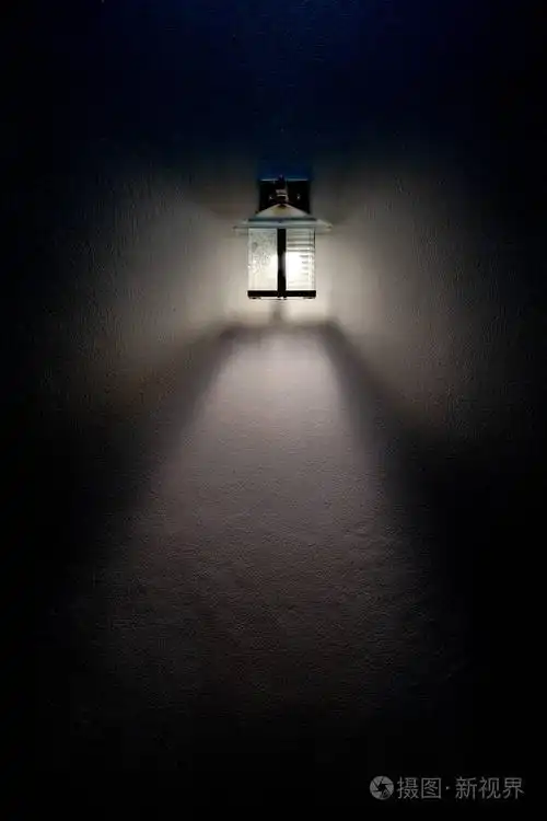 方形玻璃灯在黑暗中照亮了白色墙壁上的光束.