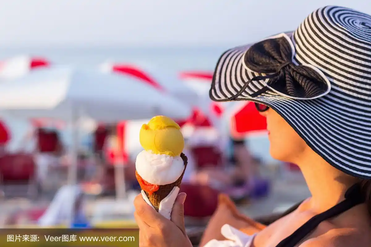 年轻女子在海滩上吃着美味的冰淇淋