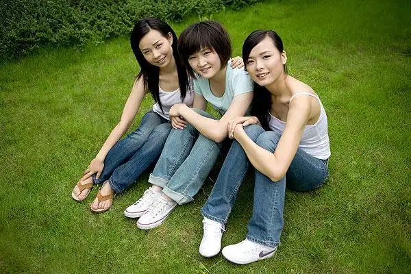 并排坐在草地上三个的女孩