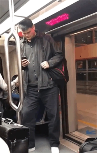 姚明现身地铁,穿着低调大方,站在门口低头玩手机,身高成亮点
