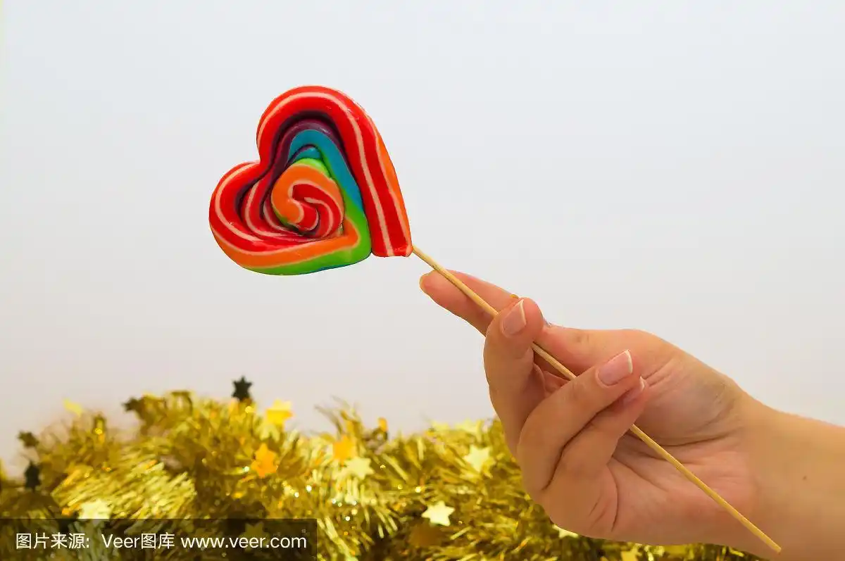 女人的手里拿着一个心形的彩色棒棒糖