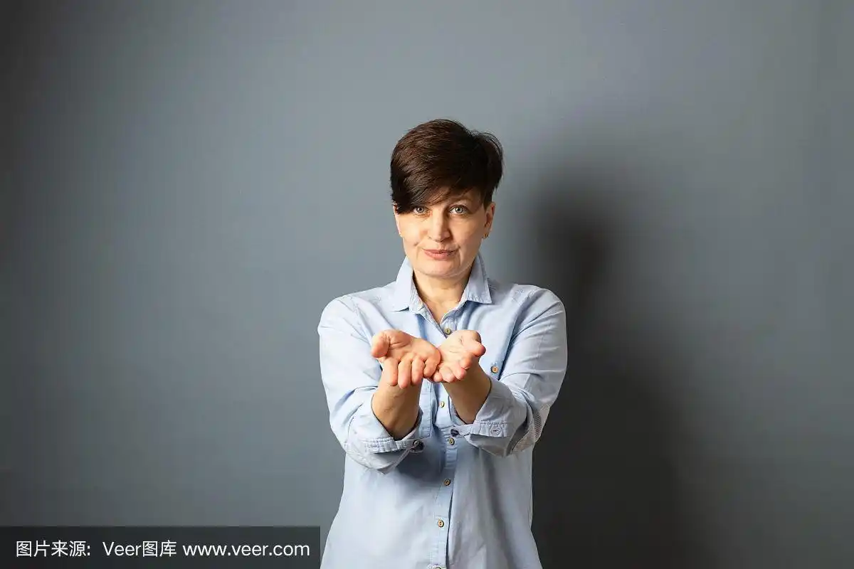 女人伸出两手,手掌向前.灰色背景上的女人肖像.副本的空间.