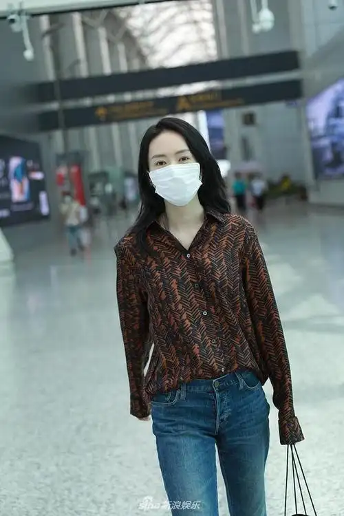 她身穿暗色衬衫搭配牛仔裤,美腿笔直修长,单手拎包姿态潇洒十足.