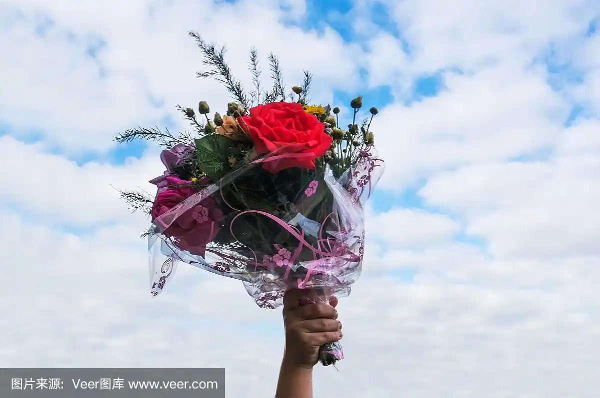 手捧一束鲜花,背景是蓝天.
