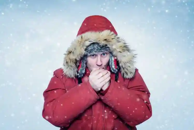 在暴风雪的天气里男子穿着棉衣双手抱团图片素材-冬天寒冷的天气男子